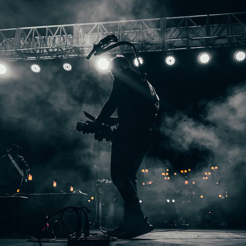 A videographer onstage at a concert filming a band